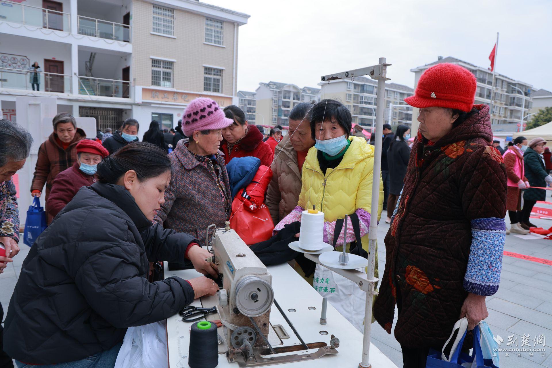 衣物縫補(bǔ)攤前，志愿者飛針走線為居民修補(bǔ)破損衣物.jpg.jpg